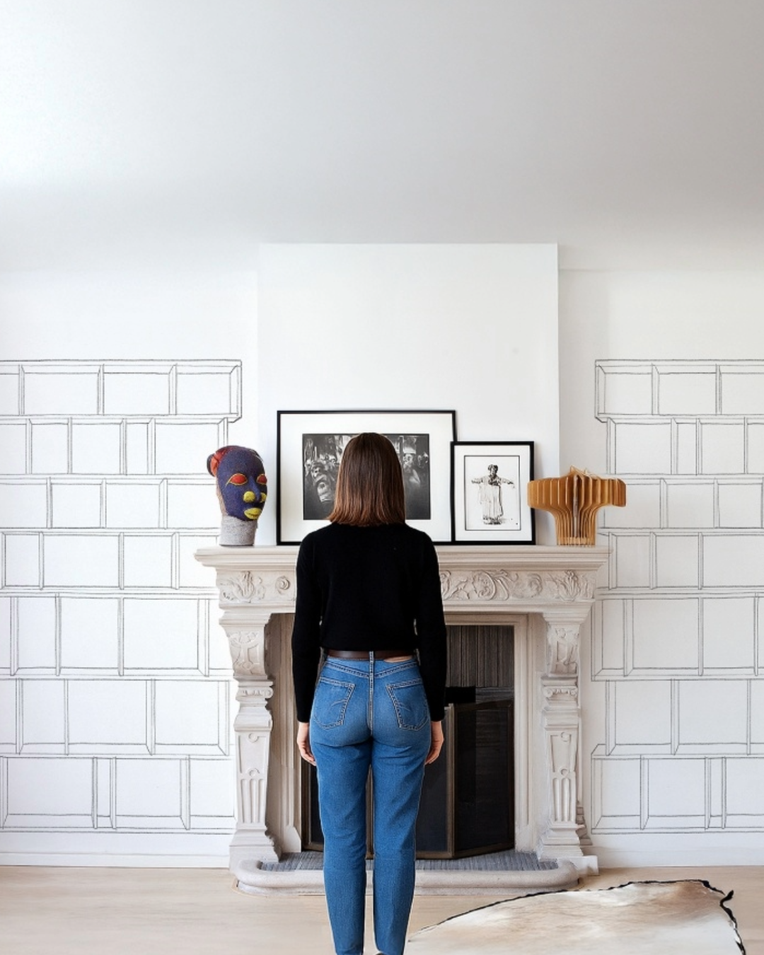 Person standing in a room with a fireplace and decorative items.
