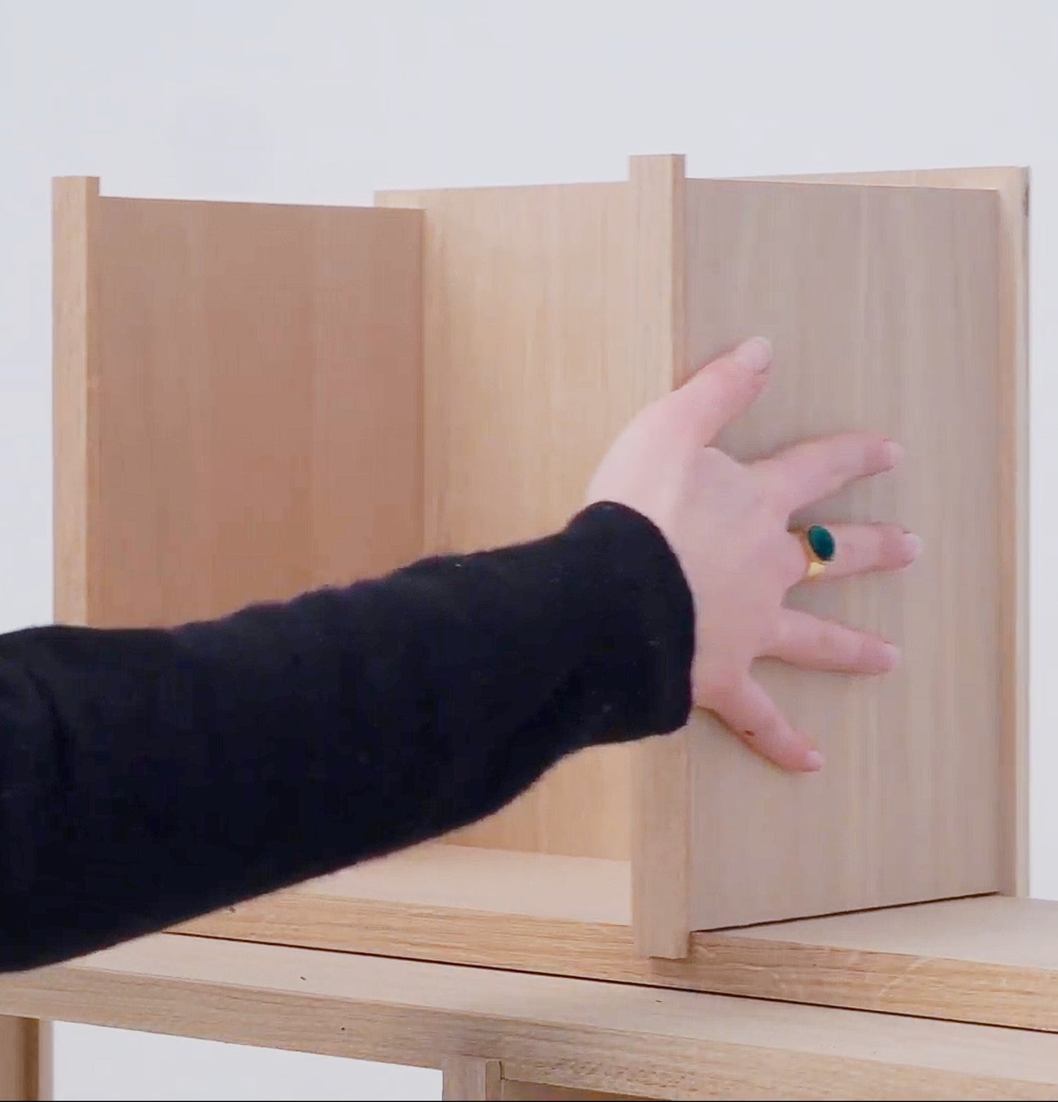 Hand reaching into a wooden box with a white background